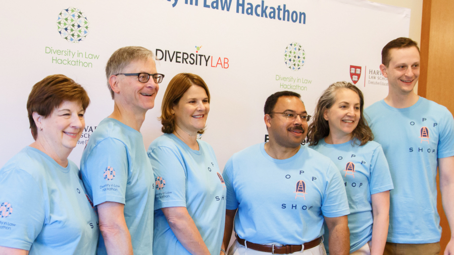 A group of people in blue shirts smile in front of a sign that says Diversity Lab