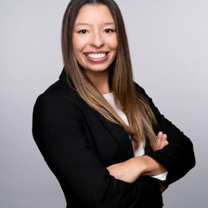 A headshot of Amber Carter, a woman in black blazer smiling at the camera