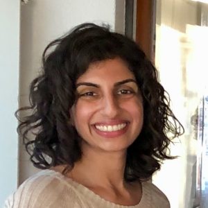 Headshot of Kavita Ramakrishnan. A South Asian woman with shoulder-length curly black hair smiles at the camera.