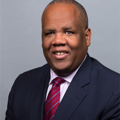 Headshot of Kareem Dale, a man with black suit and red tie smiling at the camera