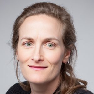 Headshot of Rebecca Aronauer, a woman smiling at the camera aginst a light gray background