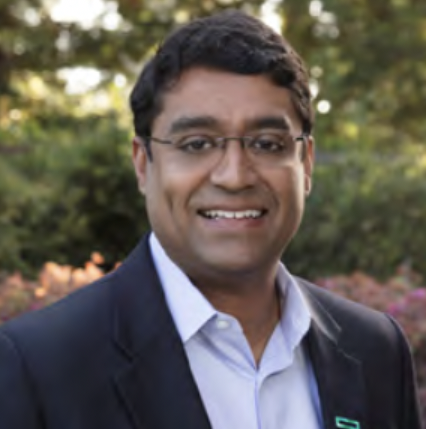 Headshot of Rishi Varma, a man in glasses stands outside, smiling at the camera