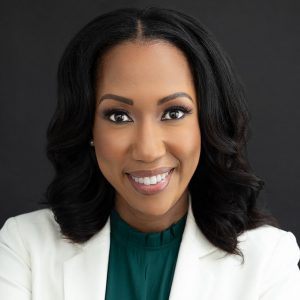 A headshot of Toni Wells, a woman in a green shirt and white blazer smiling at the camera.