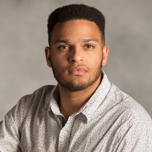 Headshot of Vance Graves, a person against a gray background posing for the camera